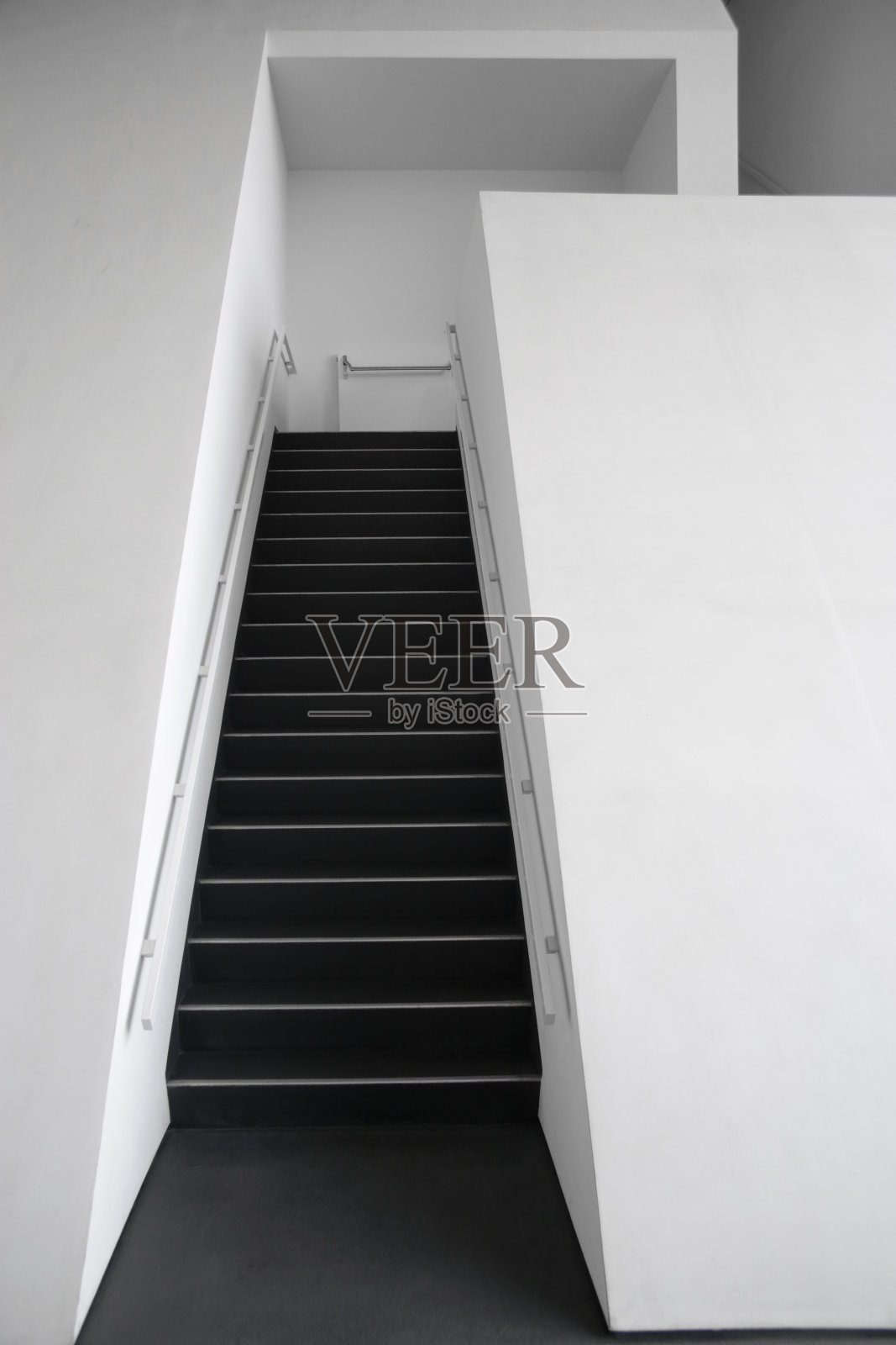 从下面观看的楼梯厅碎片的计算机图形图像。白色墙壁间的黑色楼梯。现代建筑或室内黑白背景。照片摄影图片