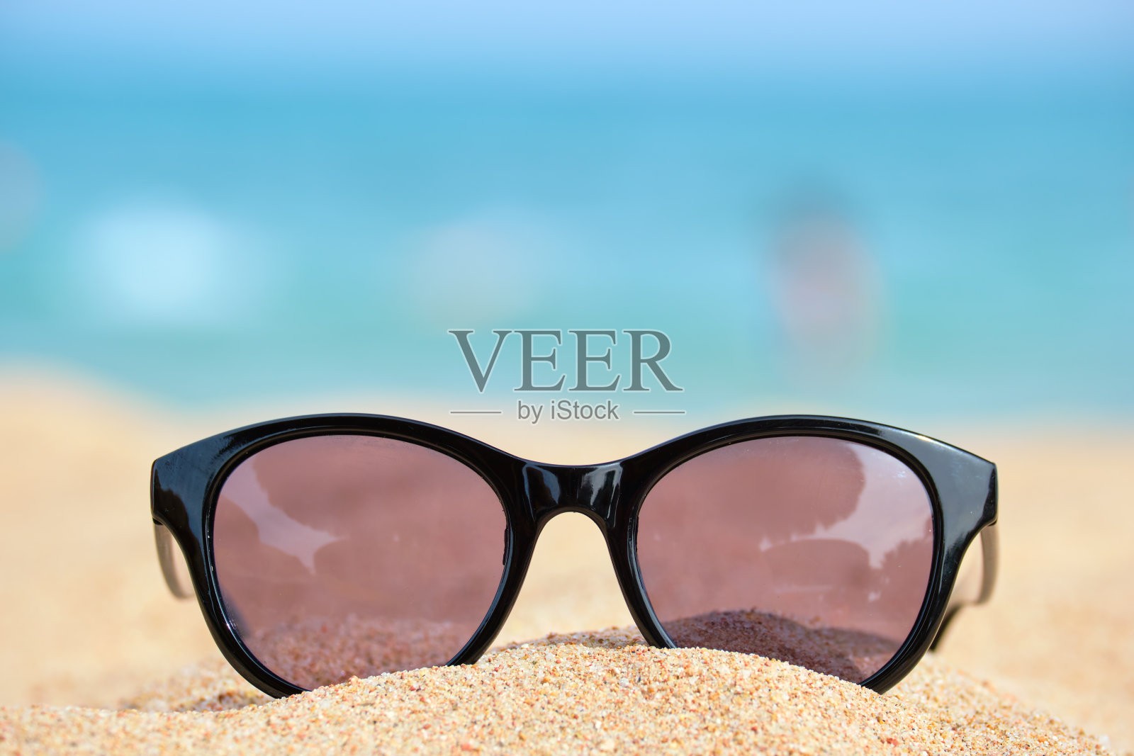 在温暖阳光的日子里,热带海边的沙滩上,黑色防护太阳镜的特写。暑假的概念。照片摄影图片