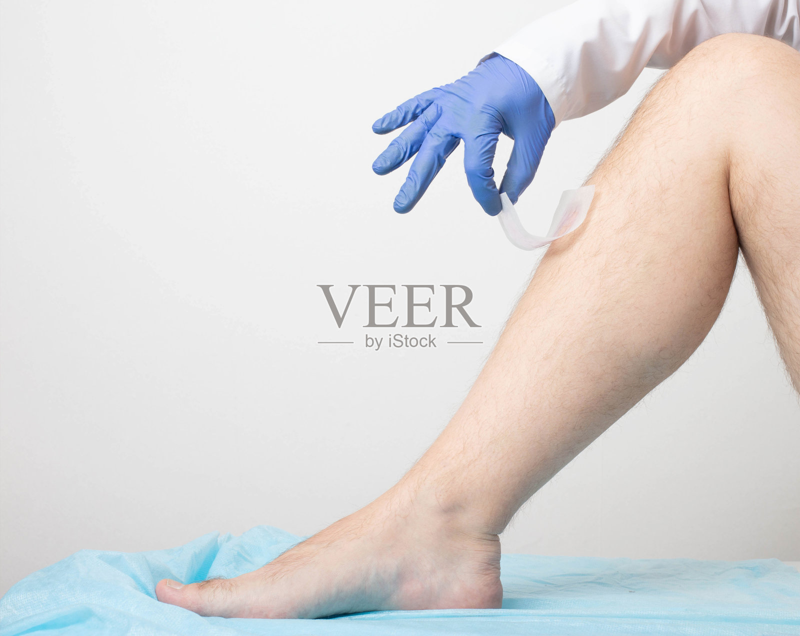 医生在白色的背景上从病人的腿毛上取下蜡条。腿毛去除概念。文本复制空间照片摄影图片