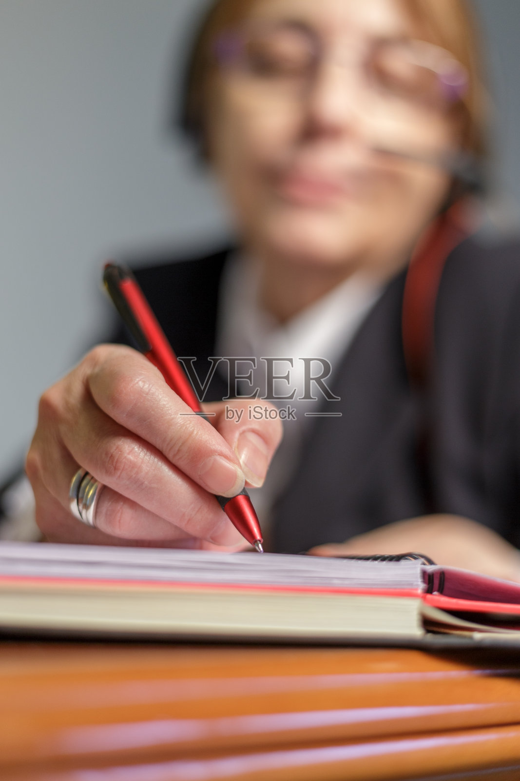 戴着眼镜的女人在呼叫中心工作。西班牙马德里,他在笔记本上写字的特写镜头照片摄影图片