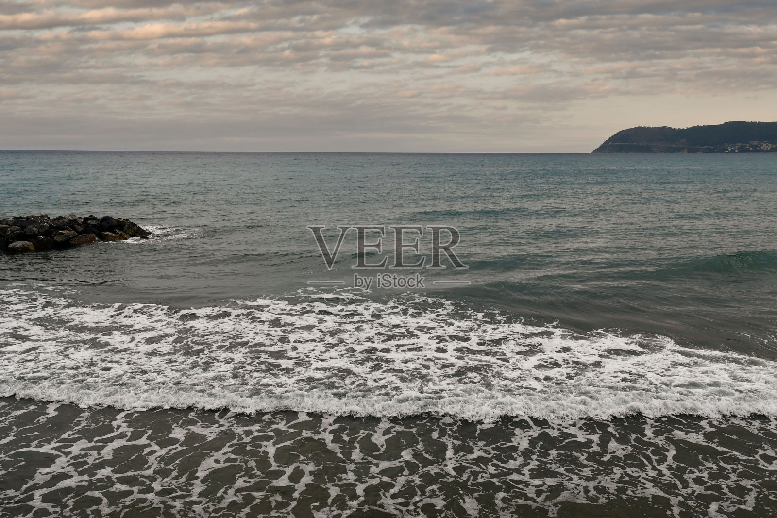 意大利,利古里亚,阿拉西奥,萨沃纳,日落时,岩石防波堤和卡波梅莱海角的海景照片摄影图片