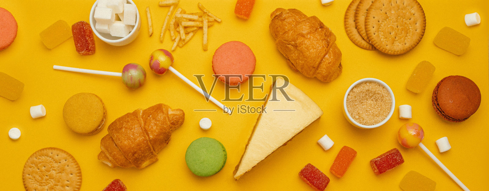 明亮的旗帜与彩色糖果和糖果在黄色背景。各种美味的糖果。顶部视图与复制空间照片摄影图片