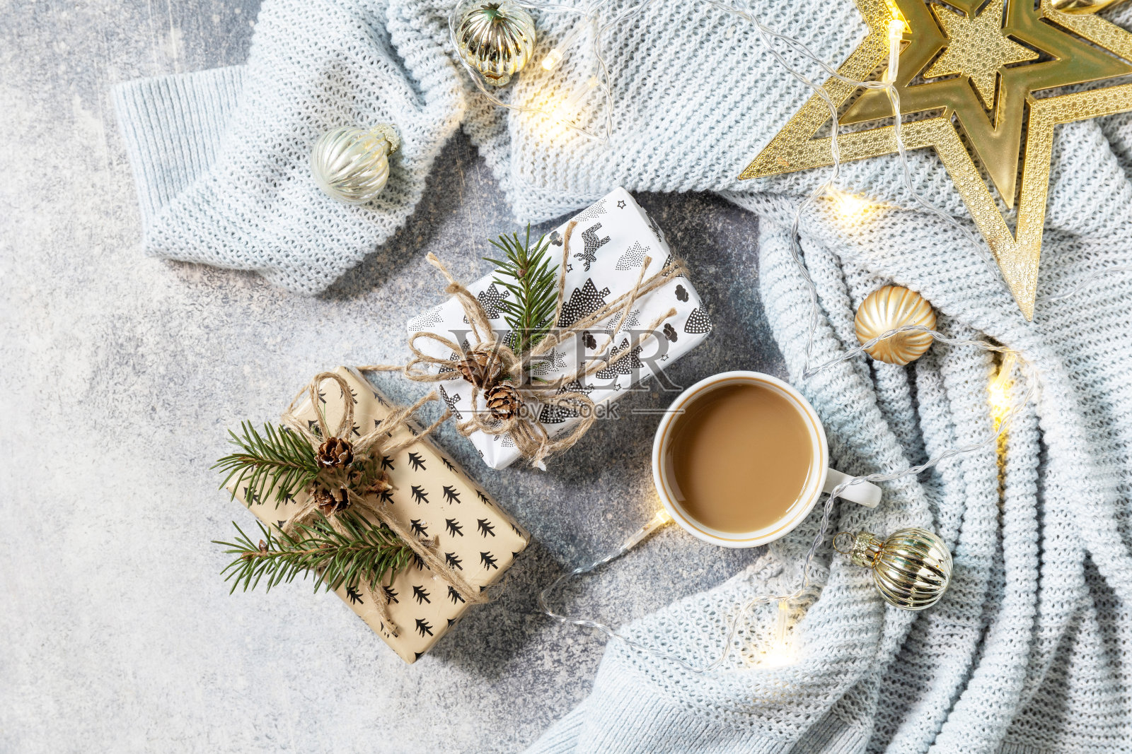 新年或圣诞节的作文。一杯咖啡,圣诞之星,针织毯子,花环和礼物在灰色的背景。冬天的概念。平铺,俯视图。照片摄影图片