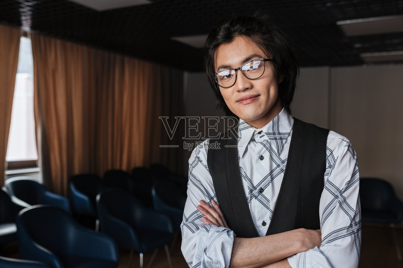 年轻的亚洲人戴着眼镜,双手交叉站着照片摄影图片