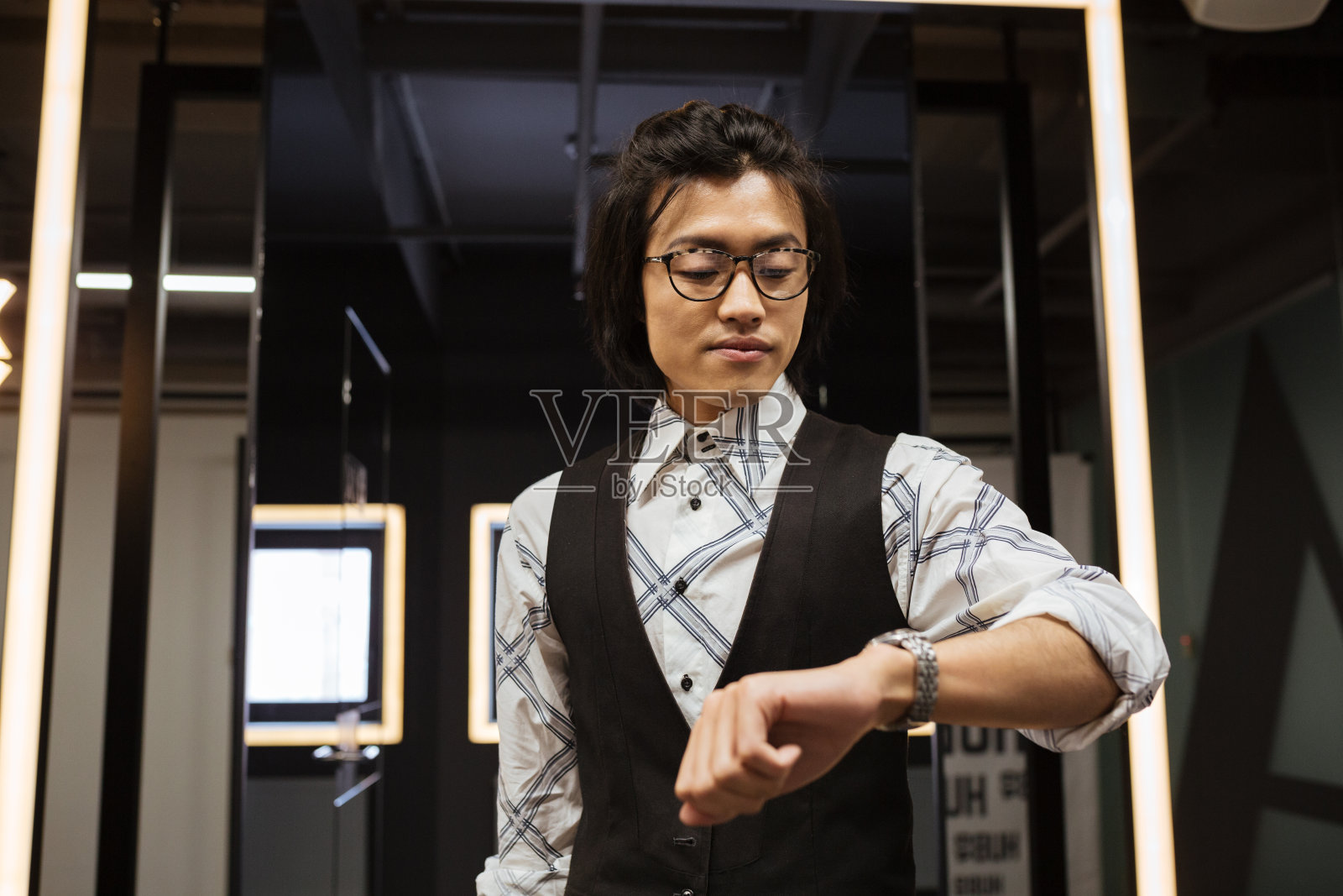 有魅力的年轻亚洲男人在看手表。共同办公的概念。照片摄影图片