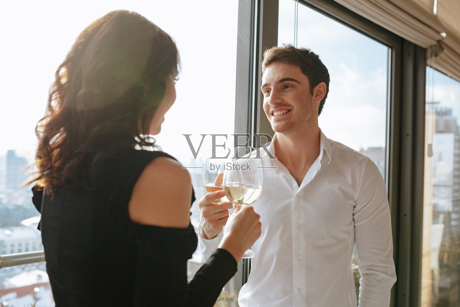 微笑的情侣站在窗边喝酒。照片摄影图片