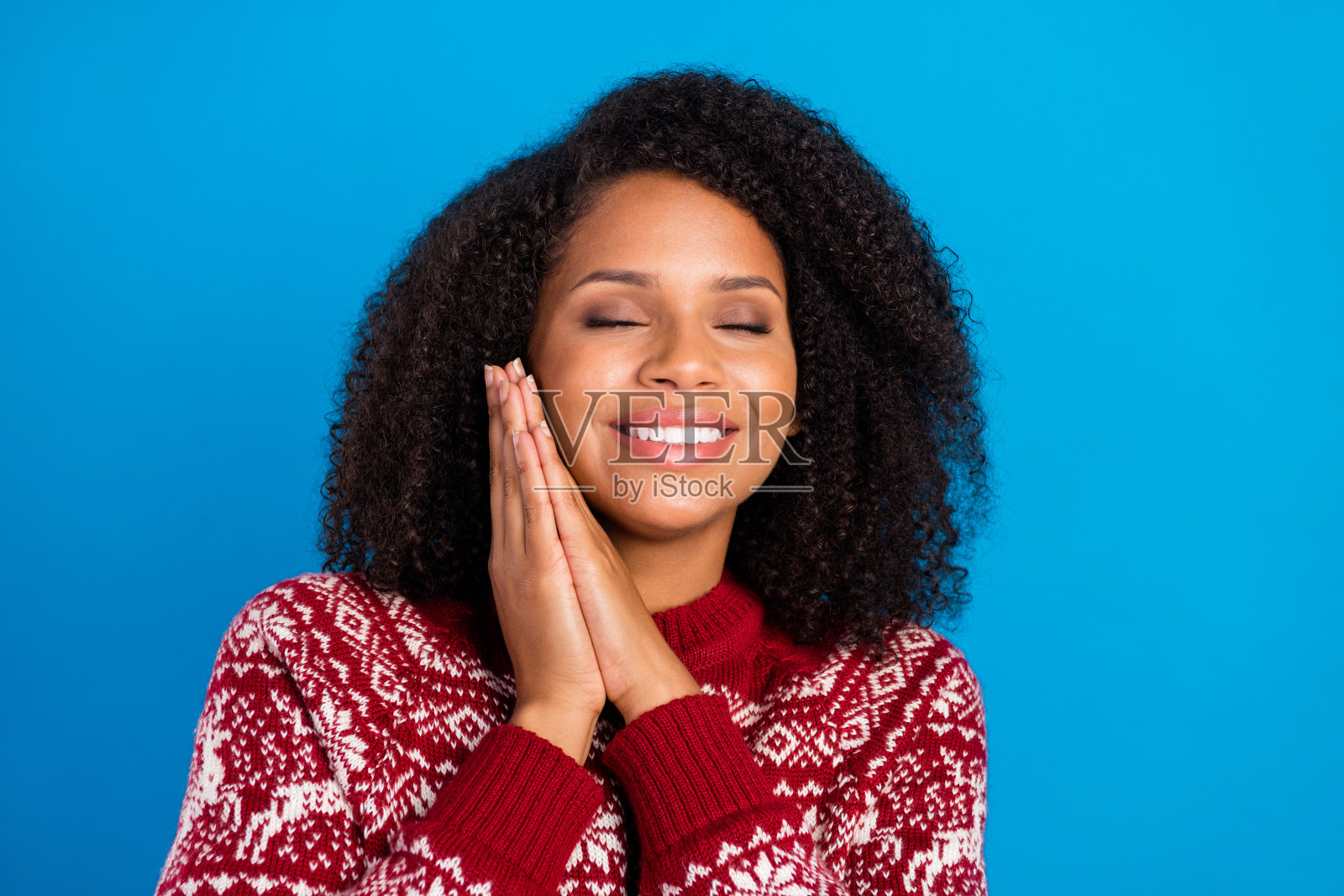 梦幻可爱的女人穿着印花毛衣微笑的手臂脸颊闭上眼睛孤立的蓝色背景照片摄影图片