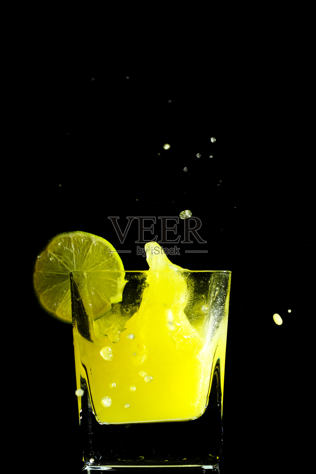 冰块掉进玻璃杯后的几滴果汁照片摄影图片