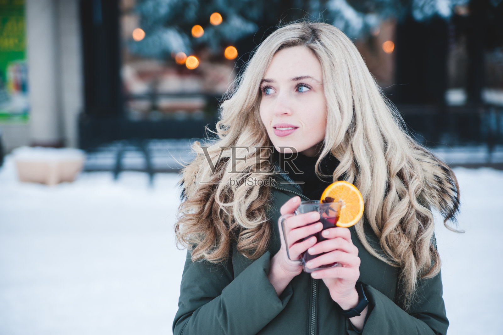 美丽微笑的女人在户外喝着热红酒。照片摄影图片