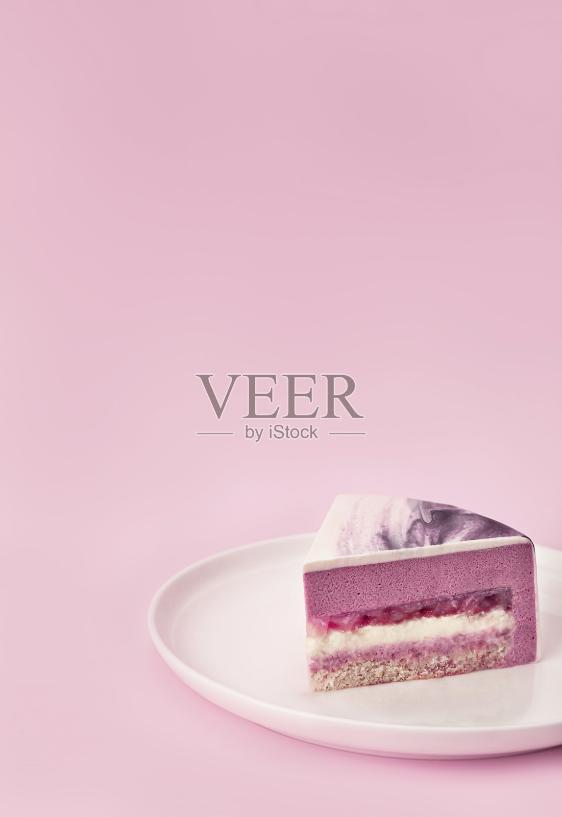 美味的荔枝和覆盆子慕斯蛋糕切片与层次和纹理显示在淡紫色的背景。特写镜头。副本的空间。照片摄影图片