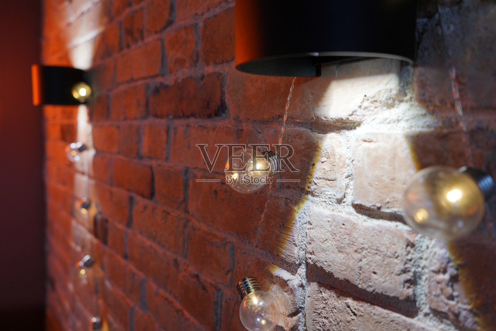 红砖墙上挂着一盏漂亮的台灯,光线沿墙漫射照片摄影图片