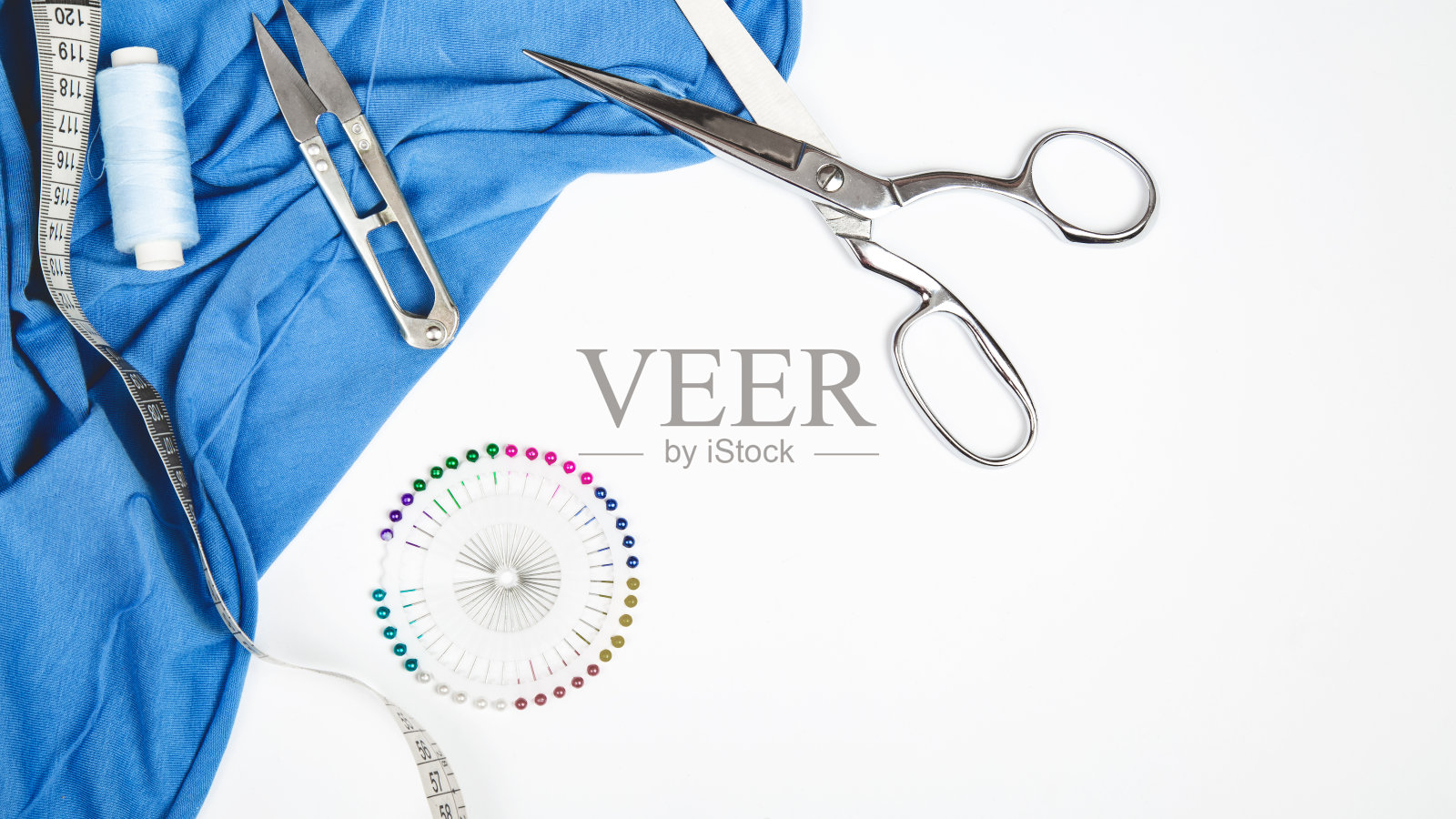 在缝纫车间。纺织品,线,剪刀,在白色背景顶部视图复制空间。照片摄影图片