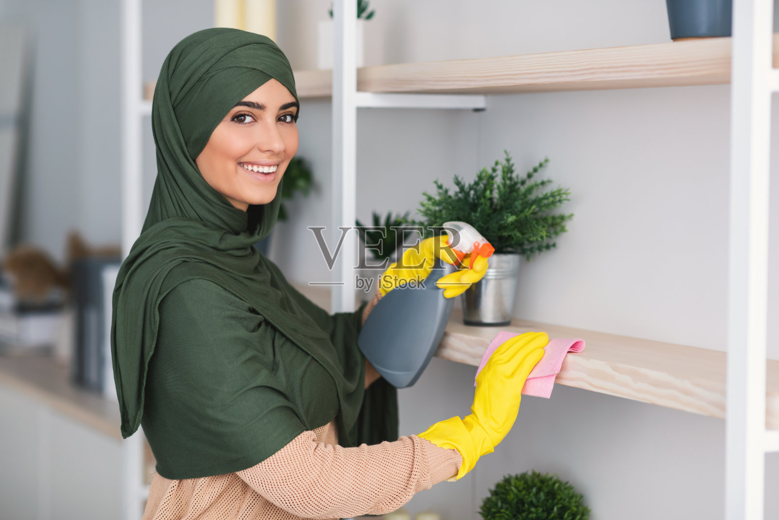 穆斯林年轻女人在家用清洁剂清洁架子照片摄影图片