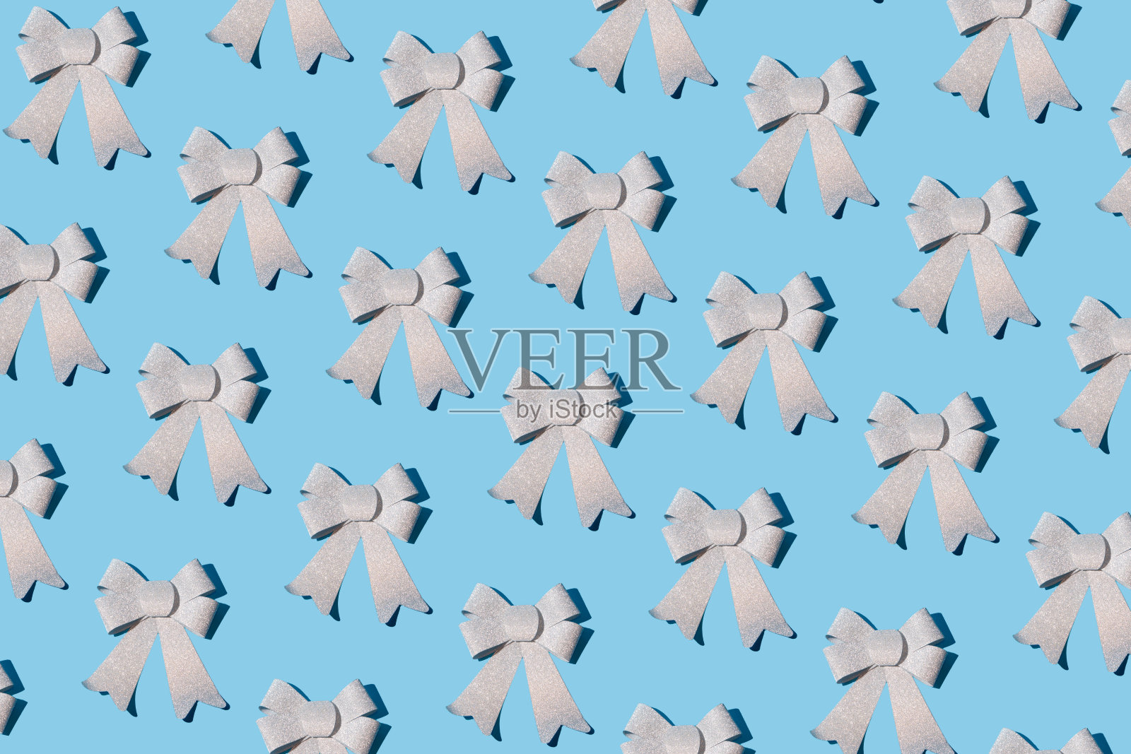 闪闪发光的银色蝴蝶结丝带图案在淡蓝色的背景照片摄影图片