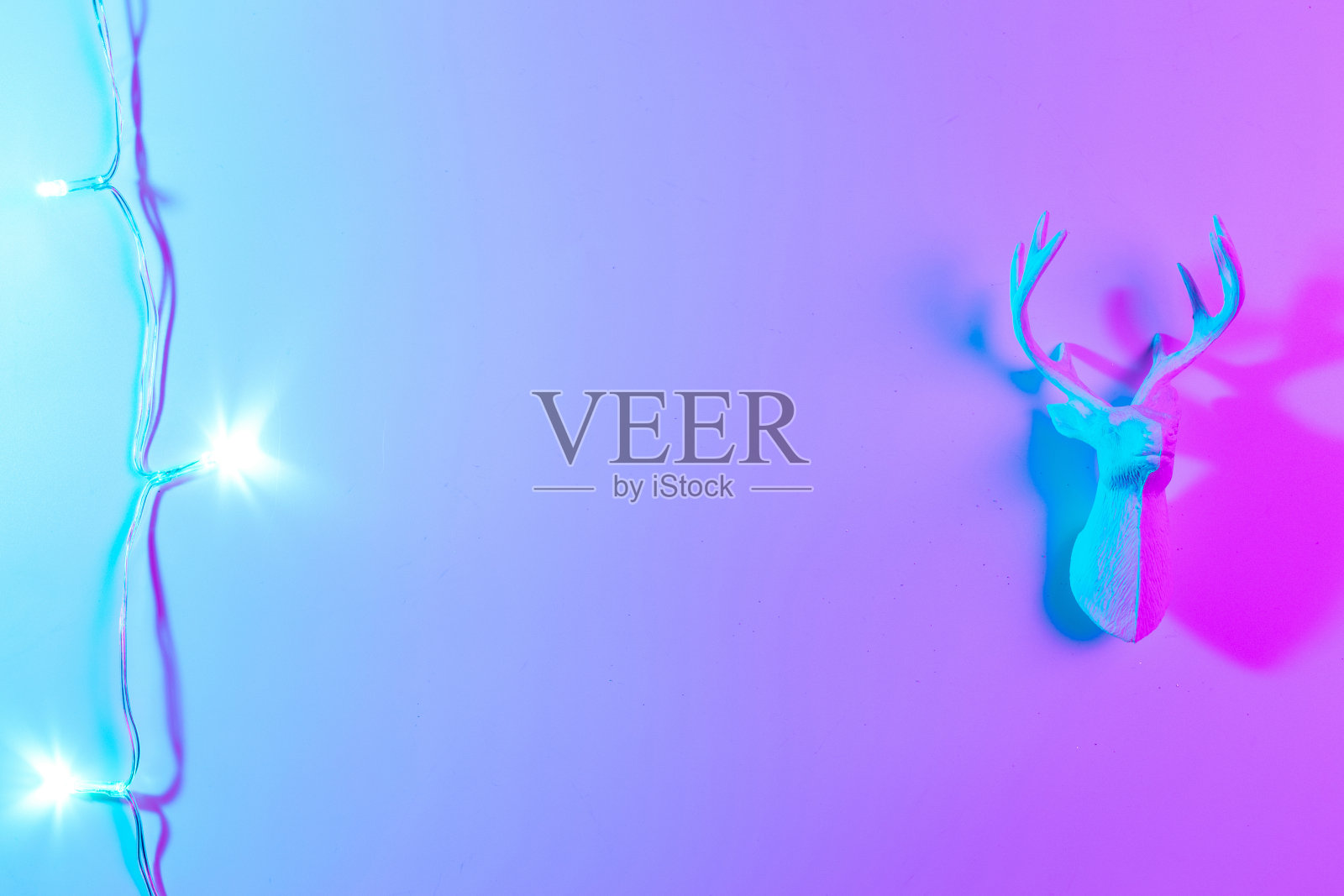 鹿灯霓虹圣诞冬季背景。最小抽象的圣诞驯鹿。假日装饰球霓虹灯梯度背景。最少的新年贺卡。照片摄影图片