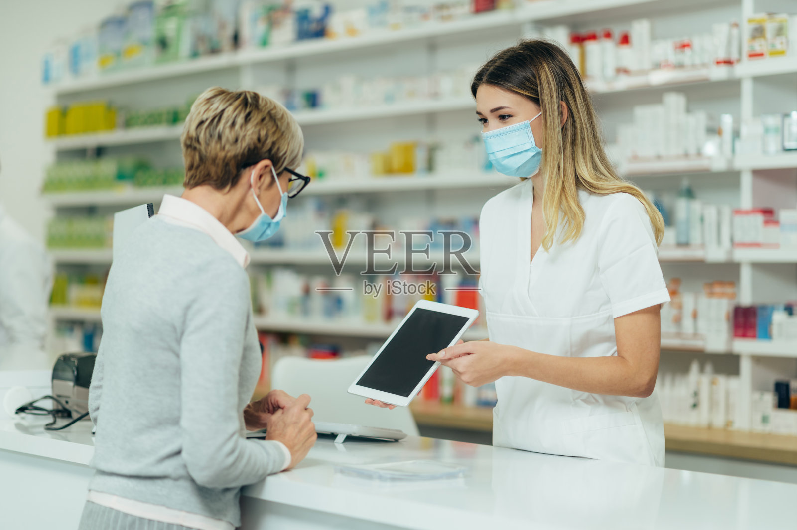 药剂师戴着防护口罩,在药房为顾客服务照片摄影图片