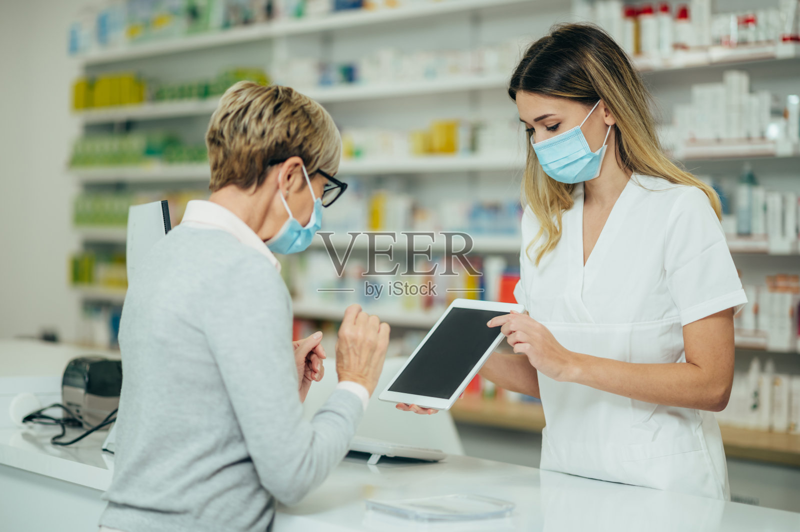 药剂师戴着防护口罩,在药房为顾客服务照片摄影图片