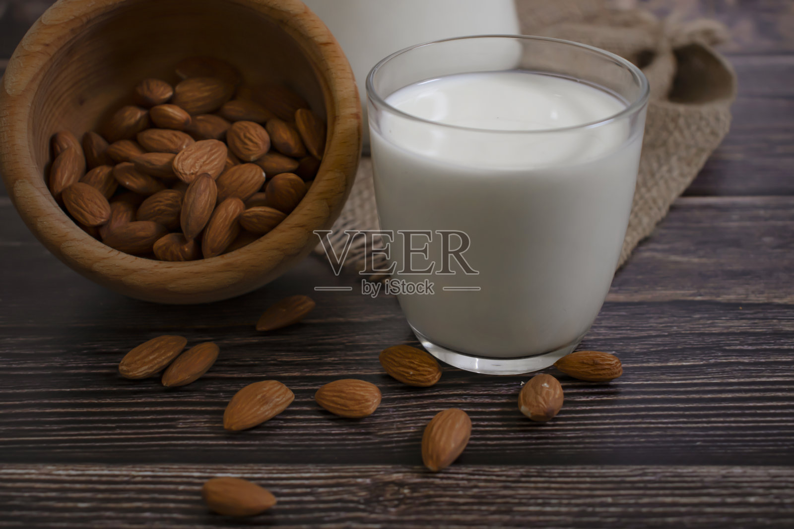 一杯牛奶,木制背景上的杏仁照片摄影图片