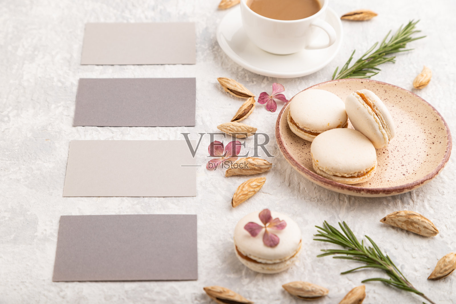 灰色的名片模型与咖啡,杏仁和马卡龙的灰色混凝土背景。空白,侧视,静物。照片摄影图片