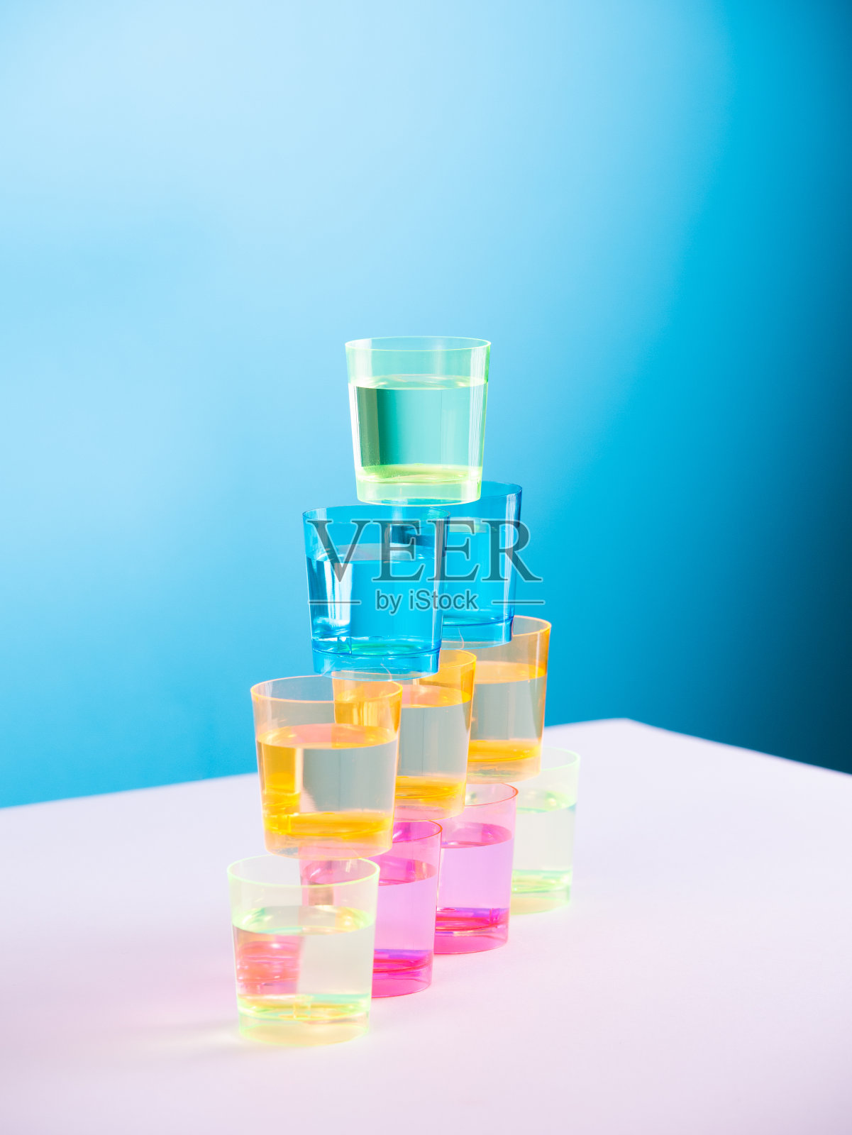 在一张白色的桌子上,有一摞彩色的玻璃杯照片摄影图片