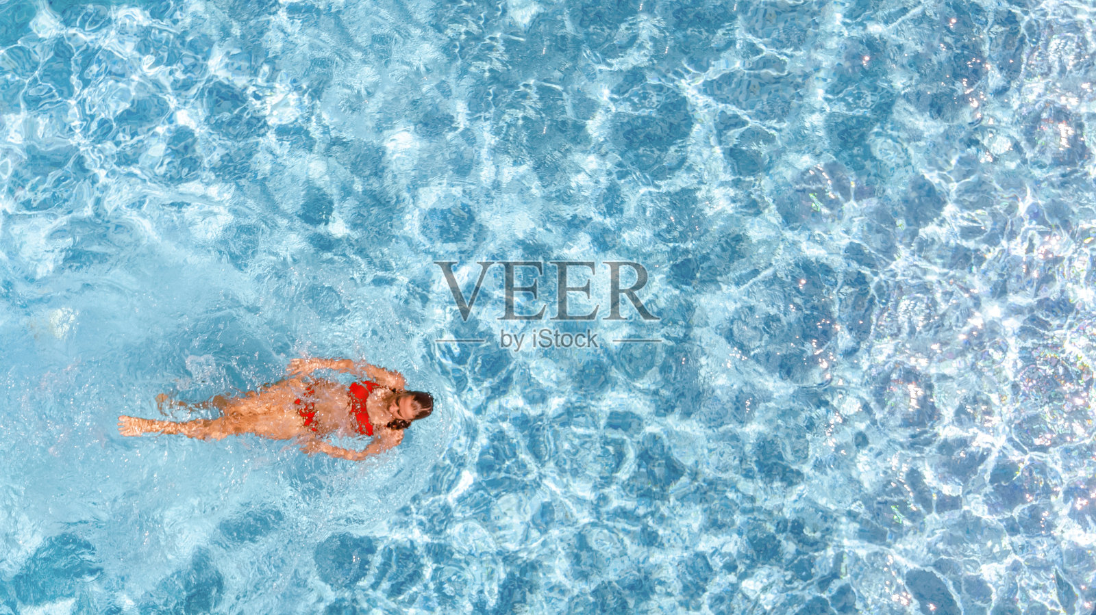 活跃的年轻女孩在游泳池空中无人机从上面的观点,年轻的女人游泳在蓝色的水游泳池,热带度假胜地照片摄影图片