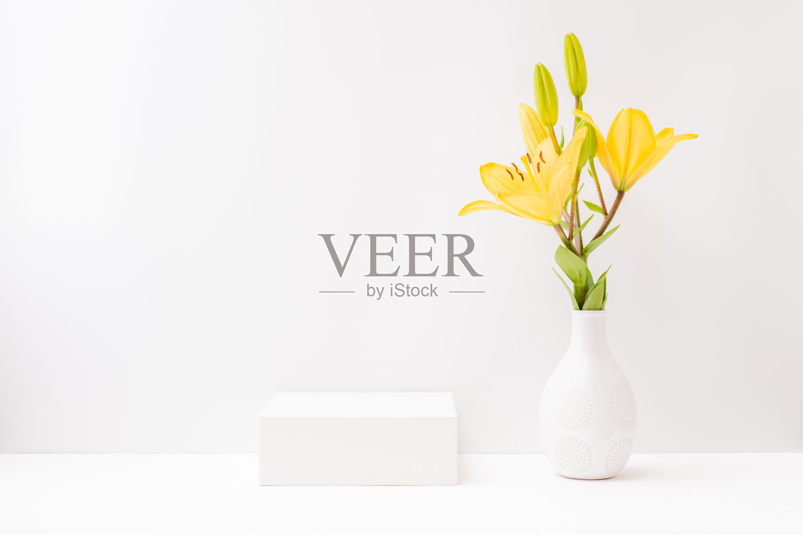 白色的空盒子和黄色的百合在一个浅色的背景花瓶。展示广告产品的模型横幅照片摄影图片
