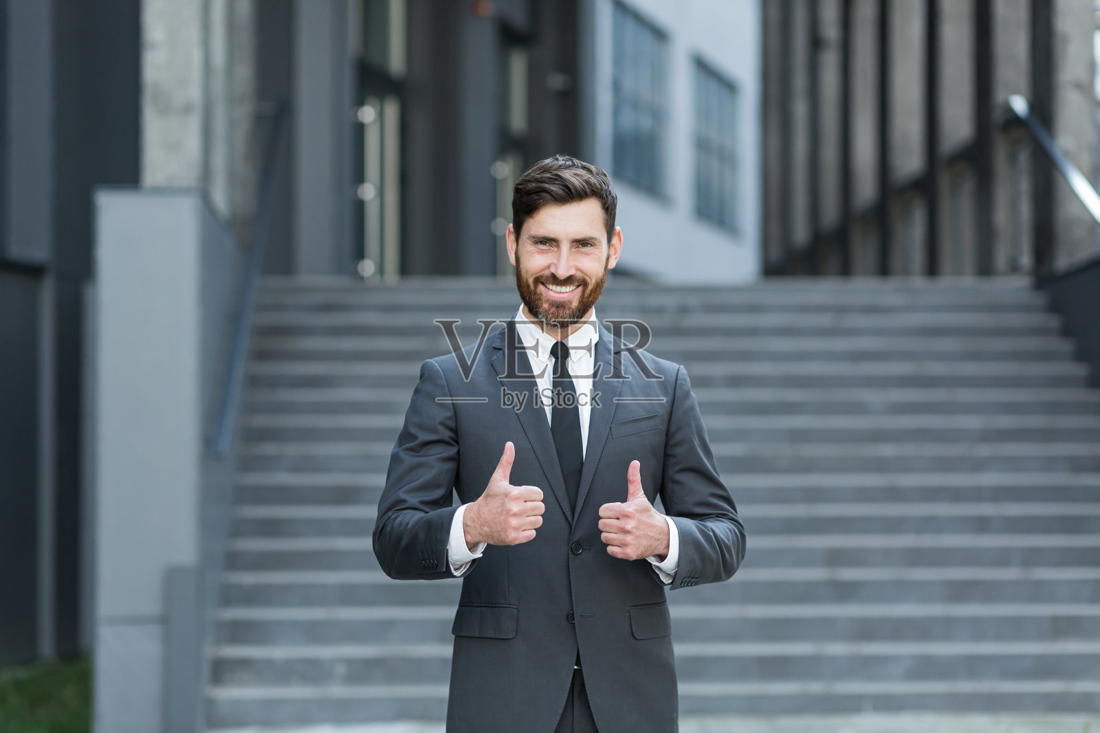 年轻的成功商人的肖像看着相机和微笑在户外,举着大拇指高兴照片摄影图片