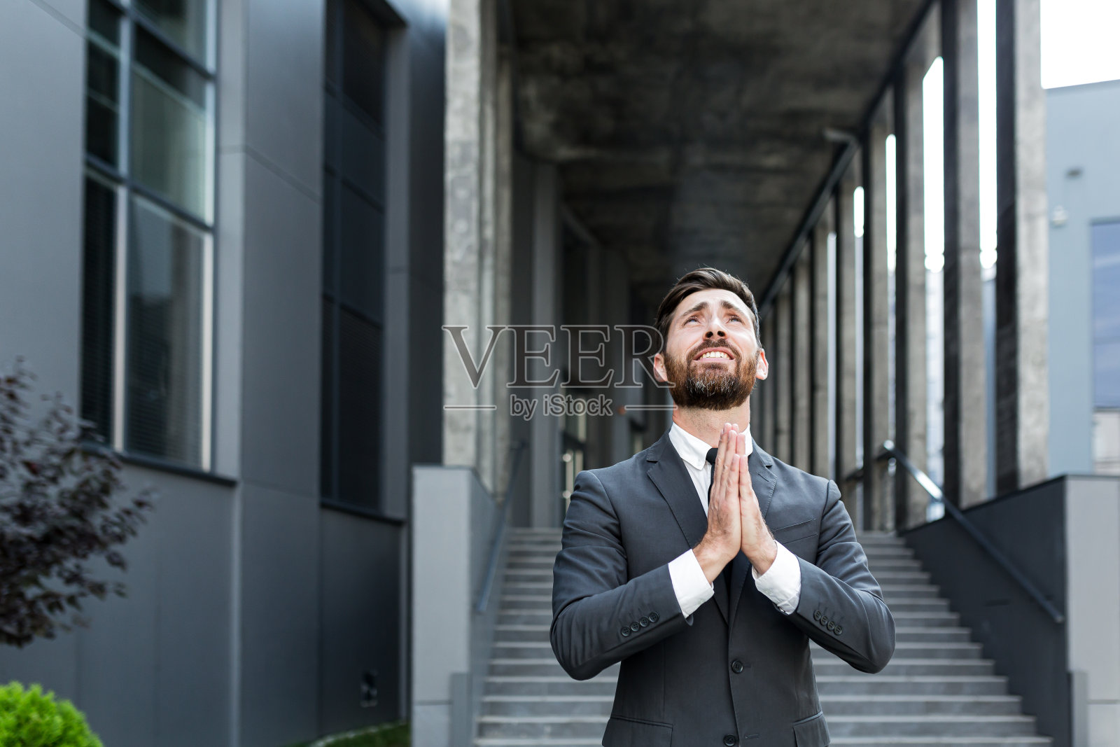画像:年轻的大胡子商人向上帝祈求成功,希望高举双手向天空。商人祈求好运,祈求一个成功的解决办法。照片摄影图片