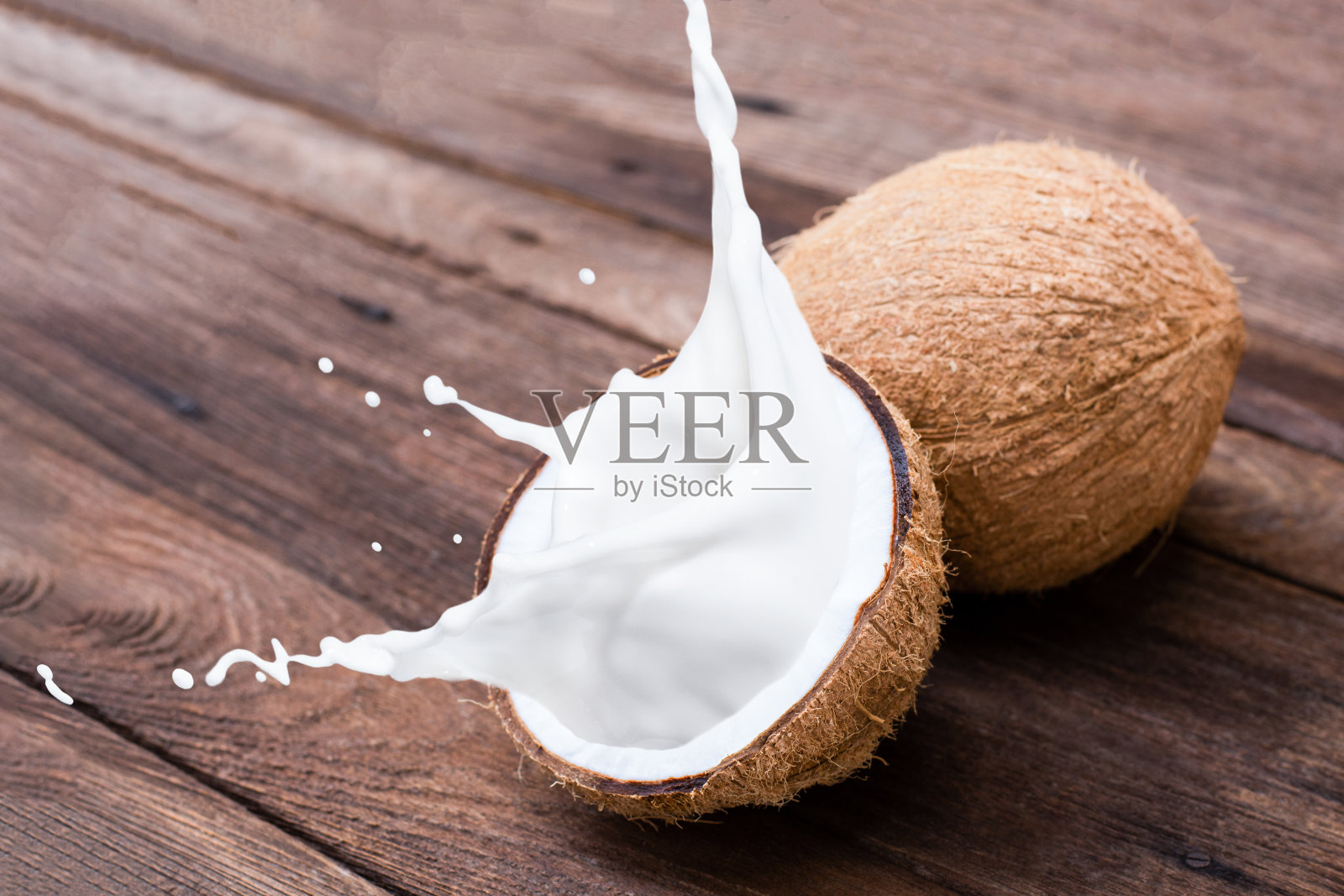 椰子汁飞溅孤立在木桌背景。照片摄影图片