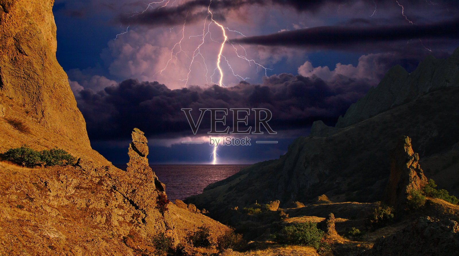 闪电掠过卡拉达格的岩石。克里米亚东部的黑海海岸照片摄影图片