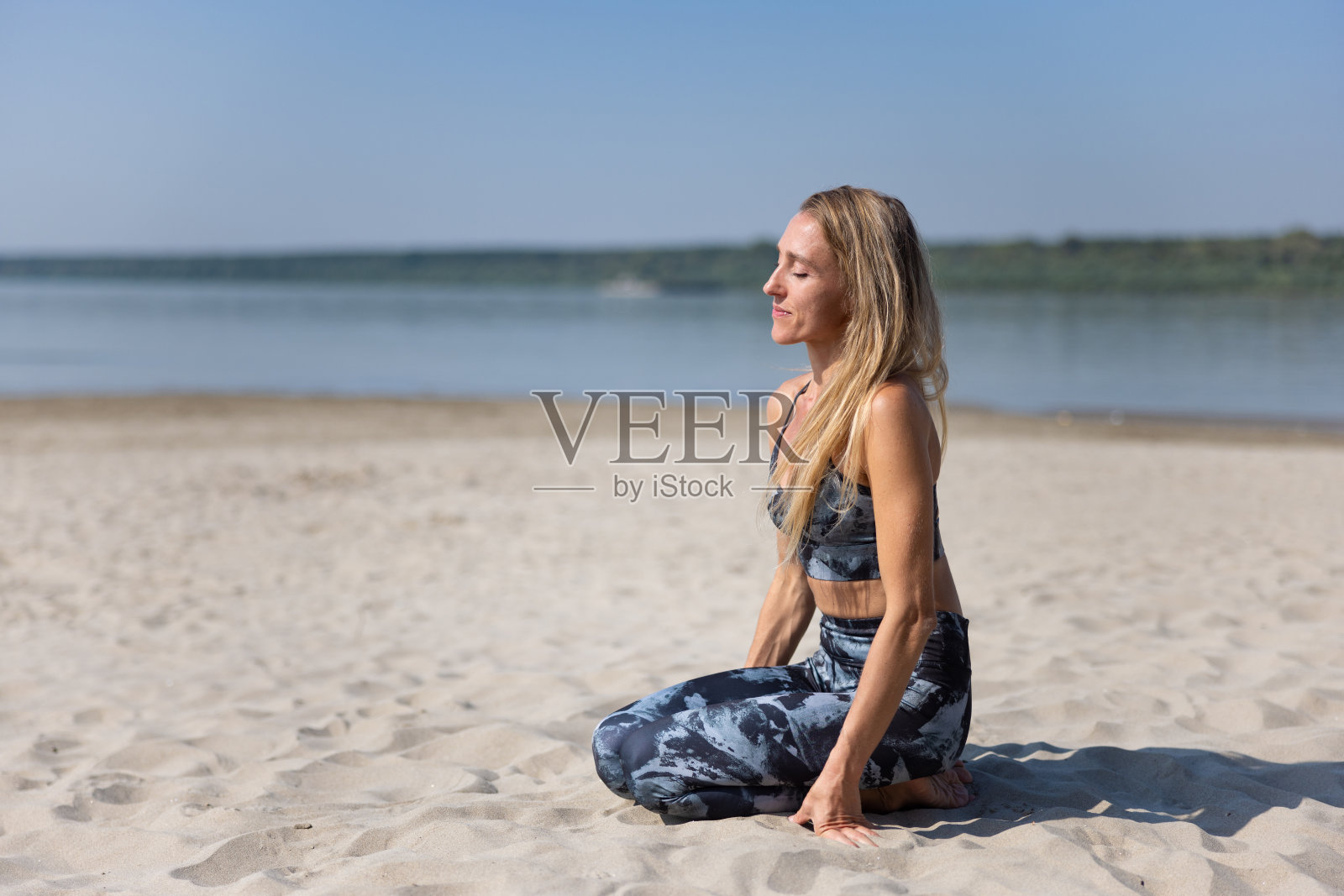 穿着瑜伽服的女人闭着眼睛跪在沙滩上照片摄影图片