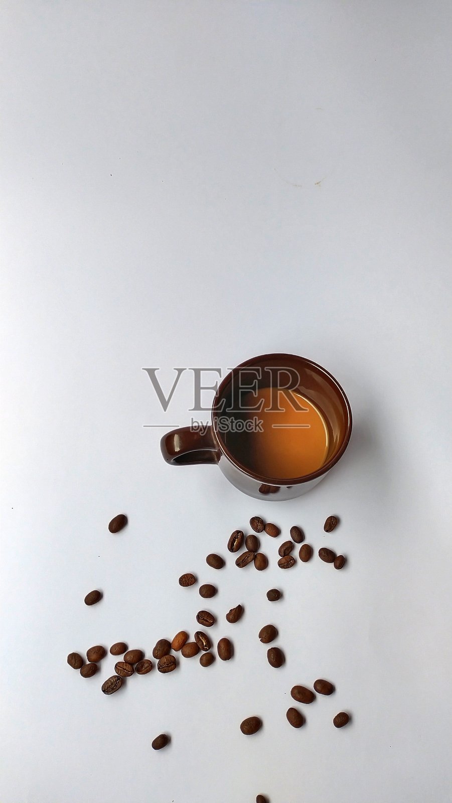 咖啡豆和杯子散落在一片完美的白色背景上。照片摄影图片