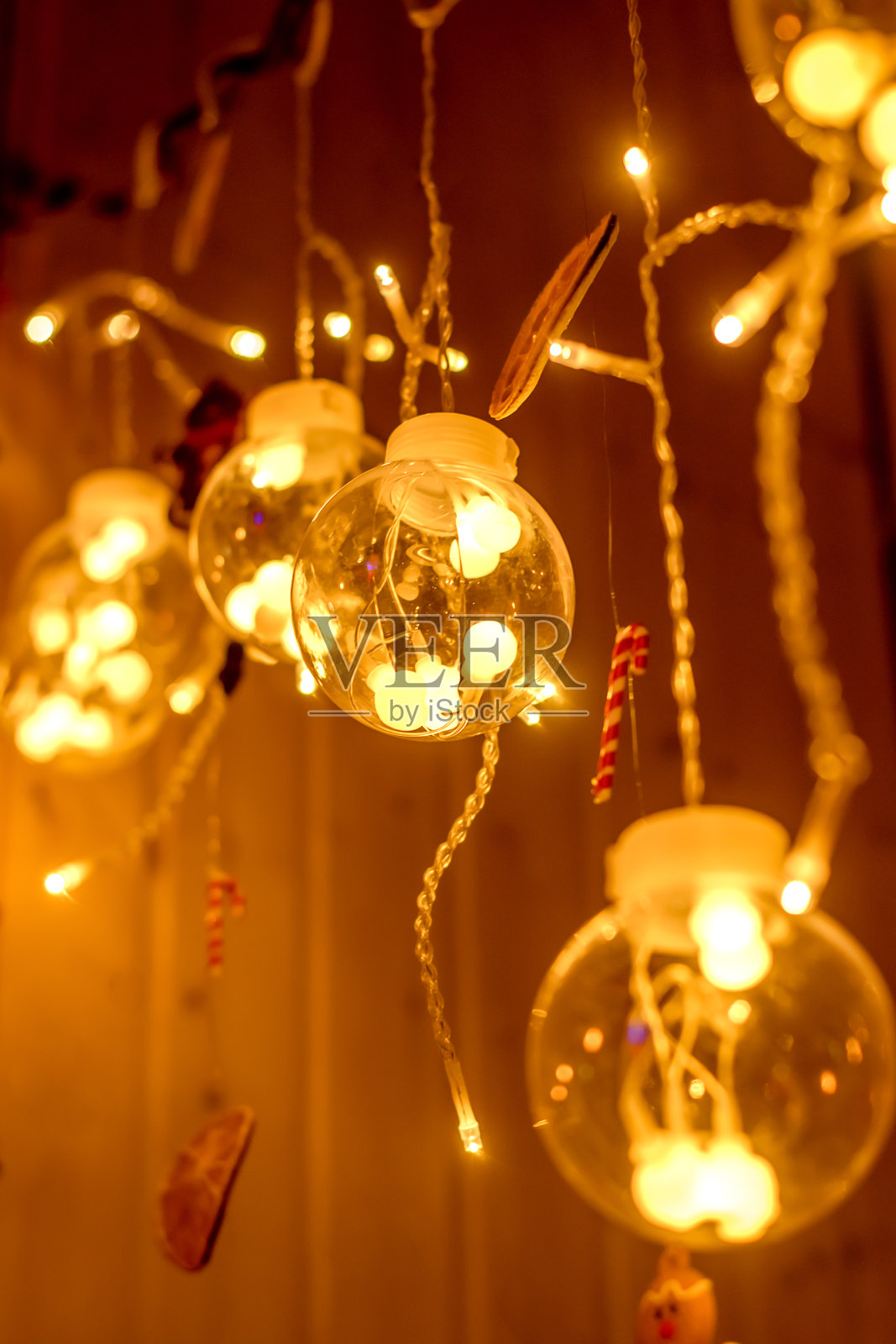 一个美丽的创意花环,玻璃球和燃烧的灯泡在黑暗的背景。节日圣诞节和新年背景。照片摄影图片