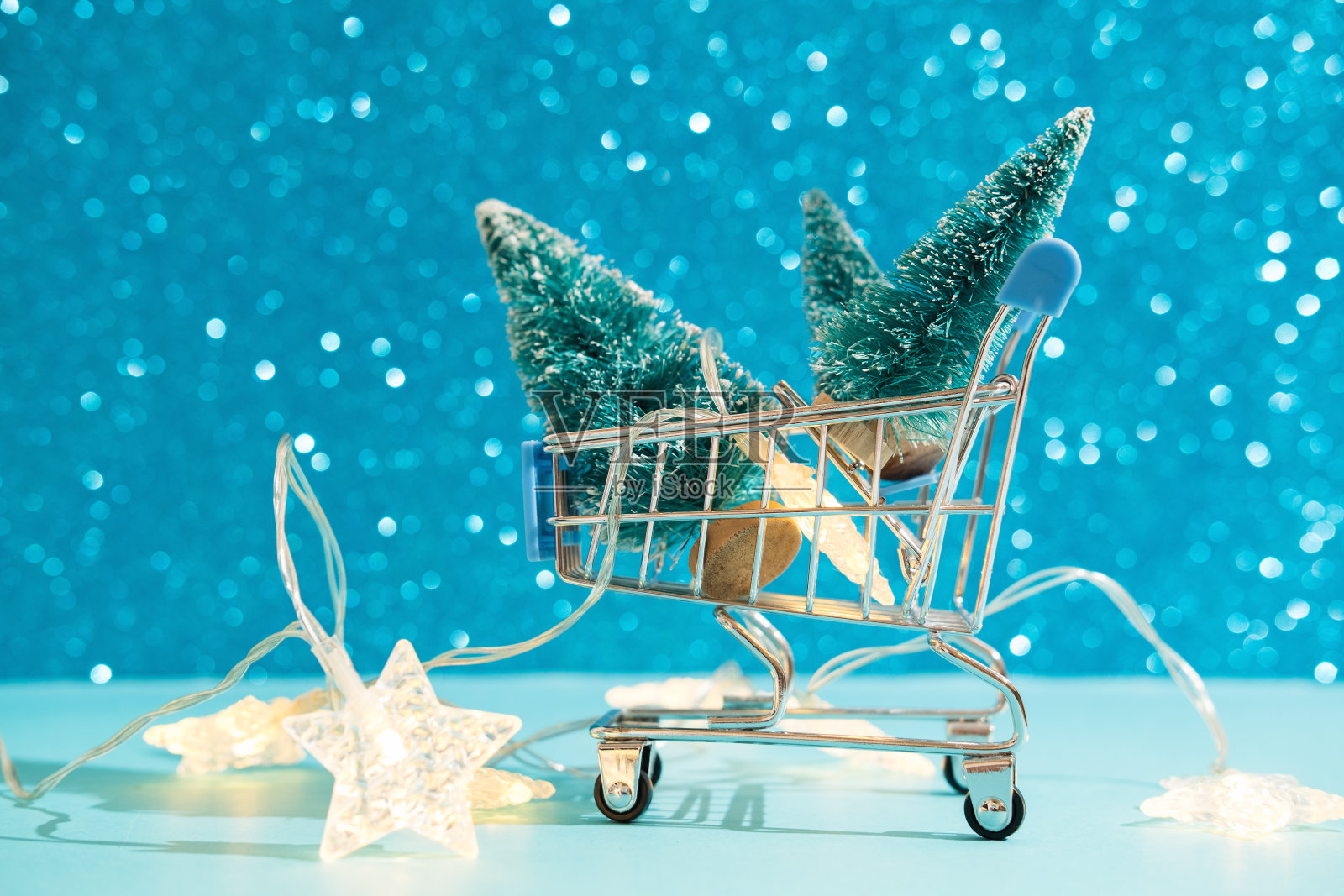 圣诞节最小的节日背景与星花环在超市篮,玩具树。抽象圣诞和新年的颜色底色为蓝色艾水蓝。亮闪闪的墙纸。照片摄影图片