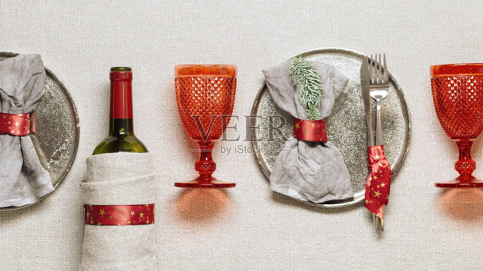 圣诞节或圣诞晚餐的餐具,亚麻布餐巾在盘子,刀,叉,红酒玻璃杯,葡萄酒瓶在乡村桌布,新年假日餐具,红色装饰,从上面看照片摄影图片