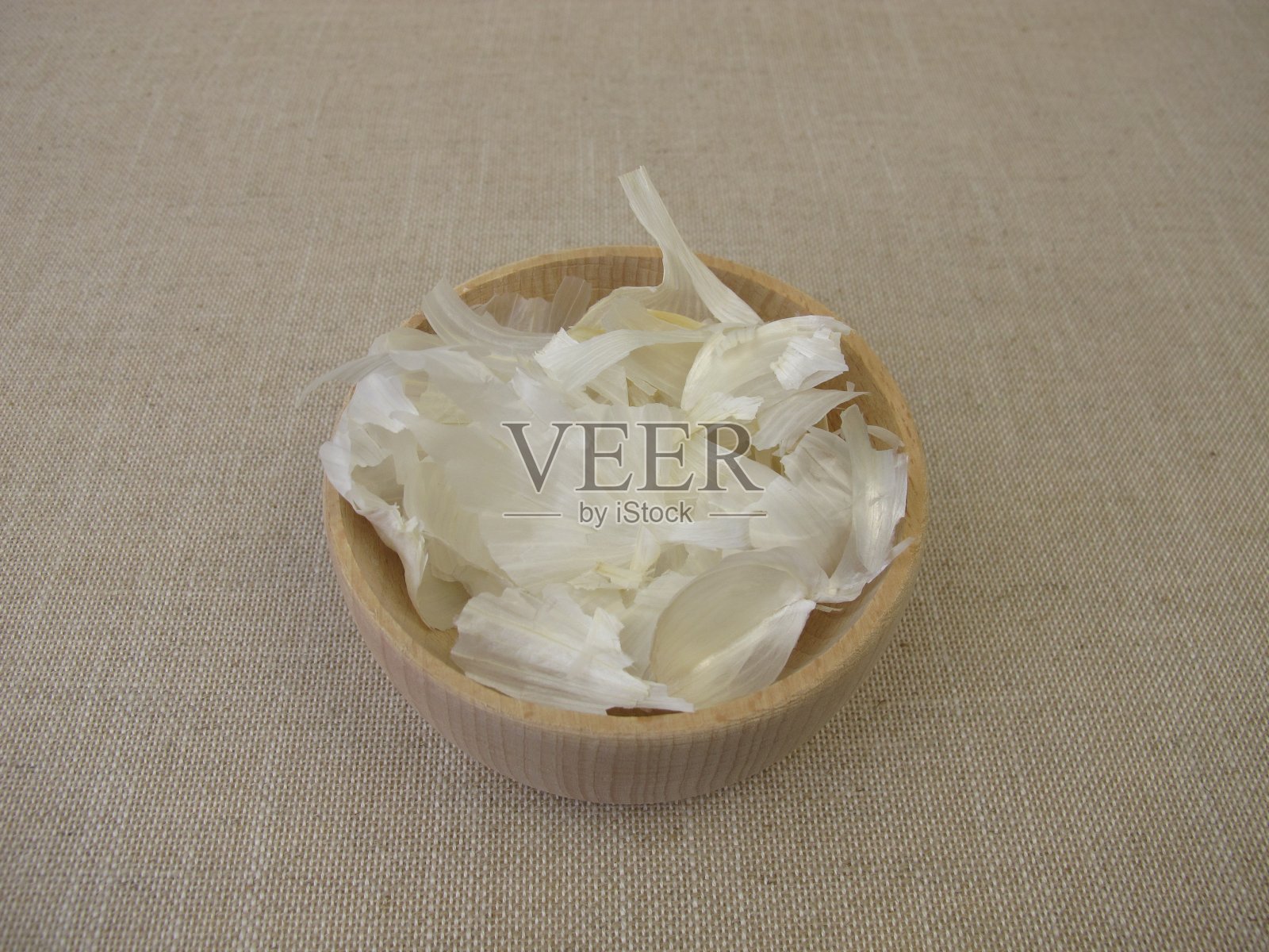 将剥了皮的蒜瓣放入木碗中照片摄影图片