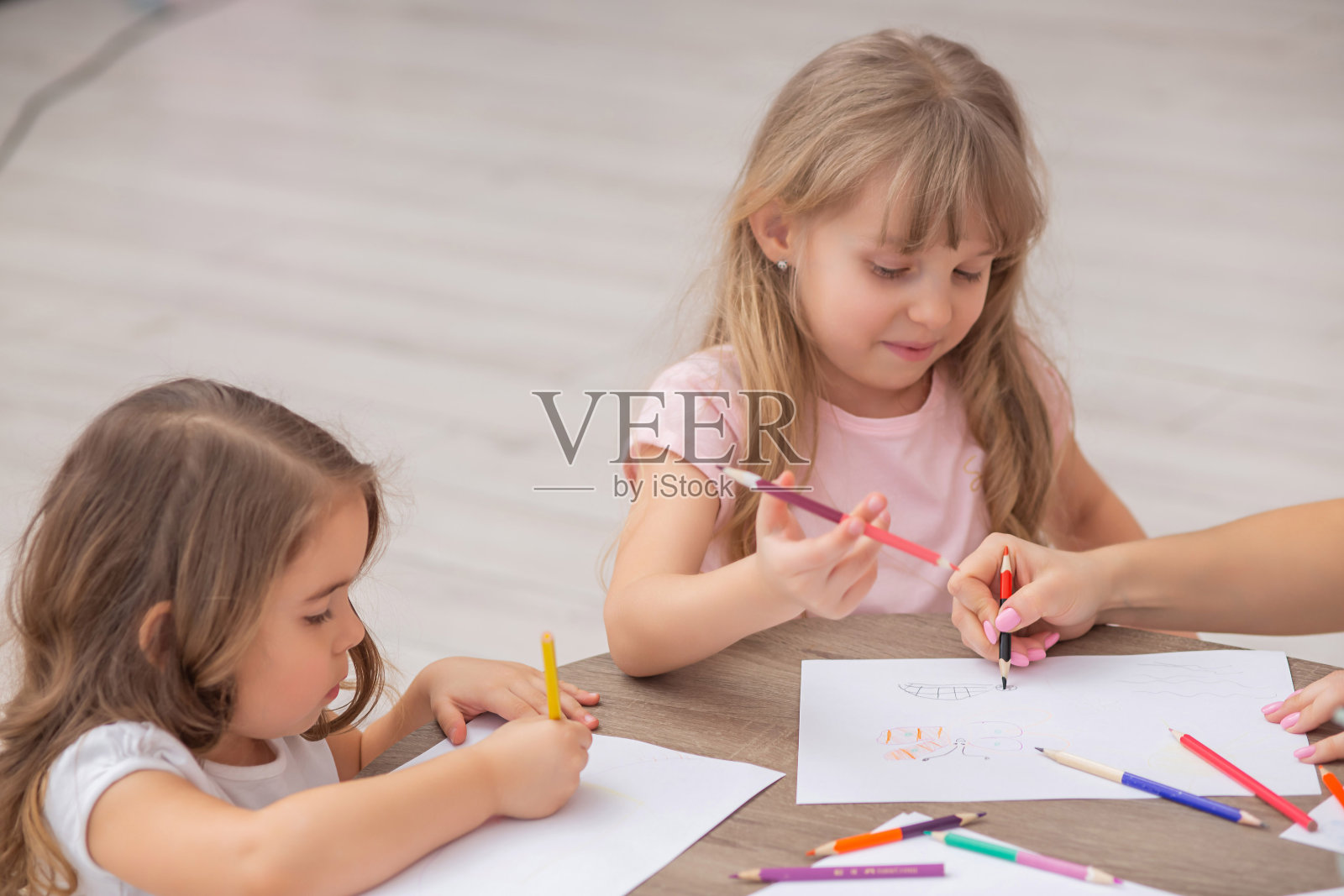 小女孩们坐在客厅的地板上画画。照片摄影图片