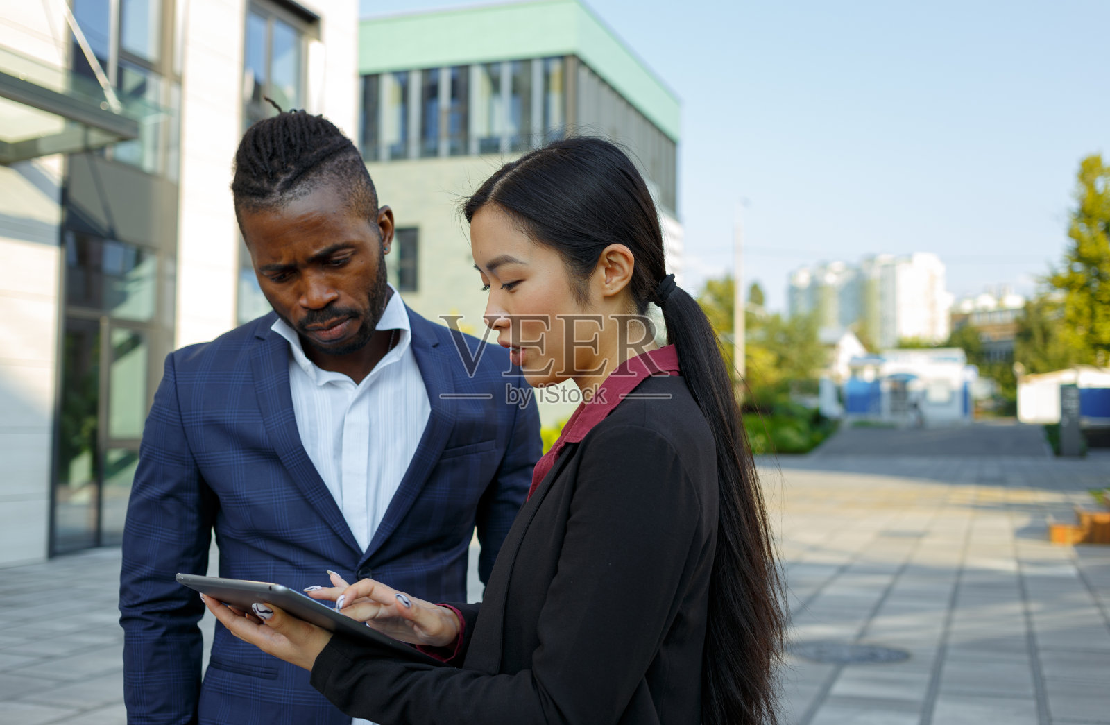 非裔美国男子和亚裔女子用平板电脑检查工作照片摄影图片