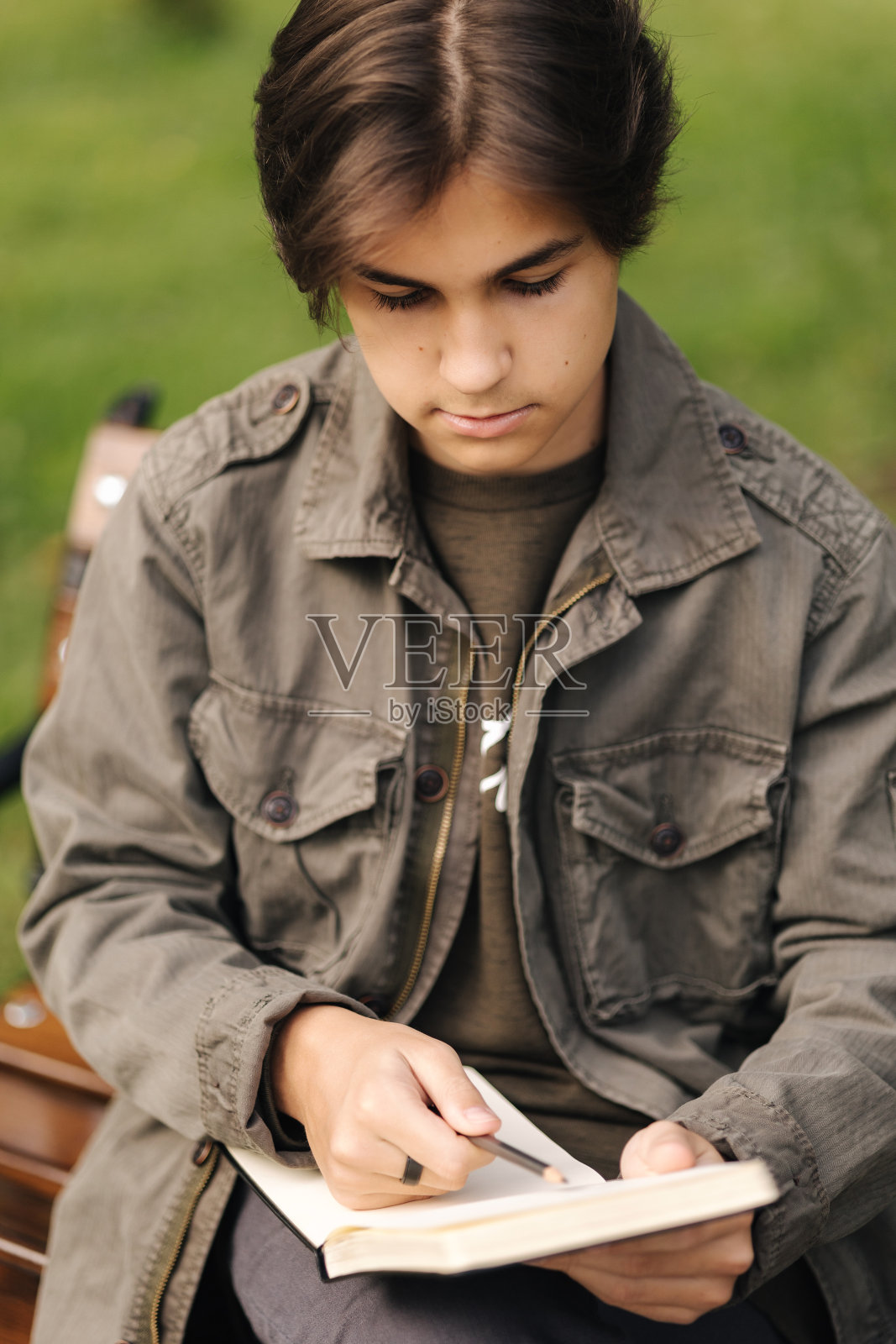 一个英俊的少年在课间休息时在他的记事本上画画。天才小男孩照片摄影图片