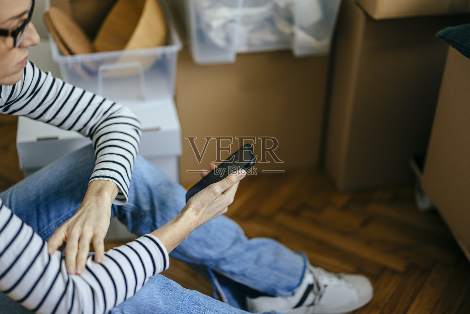 一位女士坐在地板上拿着她的手机照片摄影图片