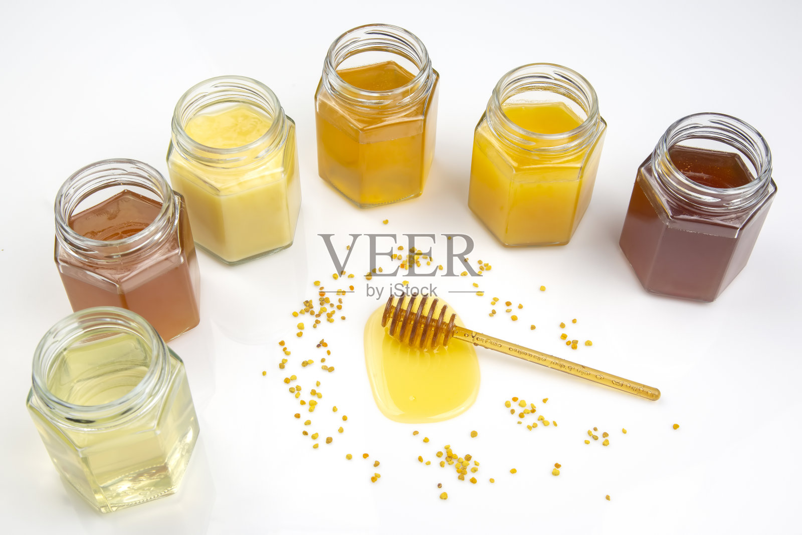 用勺子舀新鲜的蜂蜜,并在白色背景上放上不同类型的蜂蜜。有机维生素食品照片摄影图片