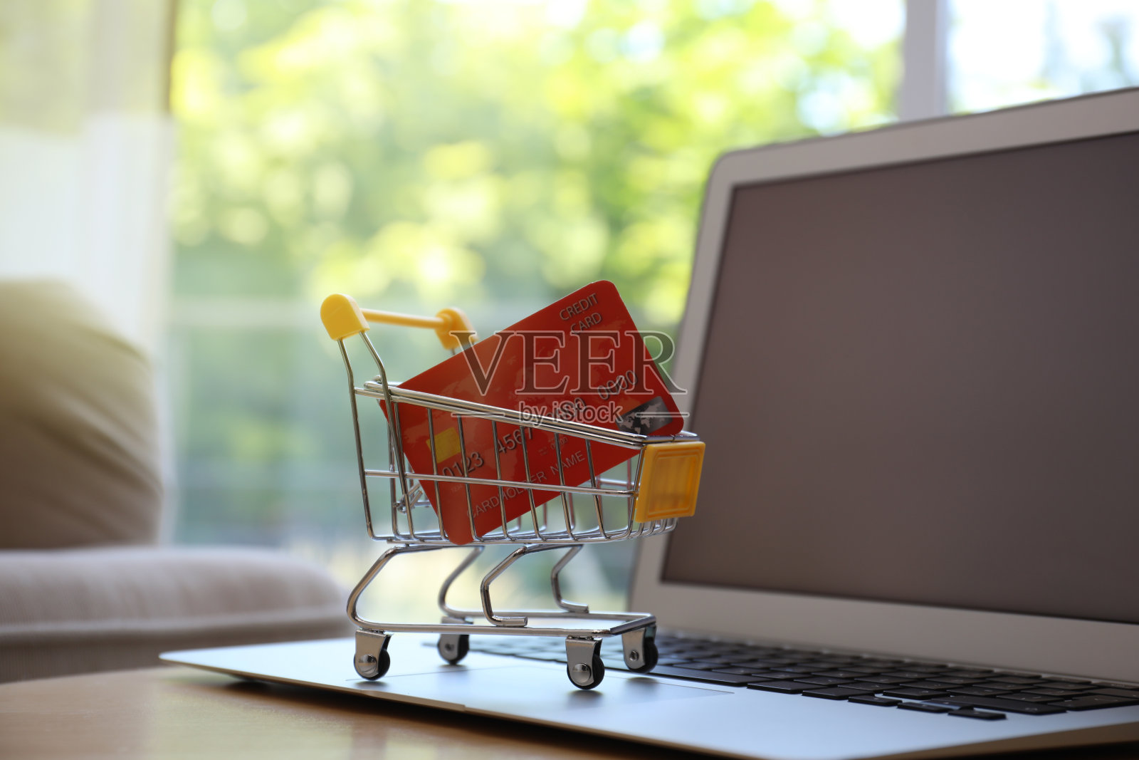 网上购物。室内的桌子上放着笔记本电脑和小推车,还有信用卡照片摄影图片