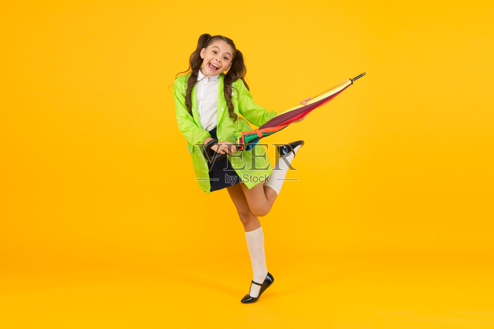 时髦的女学生小孩子带着雨伞穿防水雨衣。防水的衣服。秋天的雨。去上学。防水的衣服。雨是完成了。秋天下雨。等待下雨天照片摄影图片