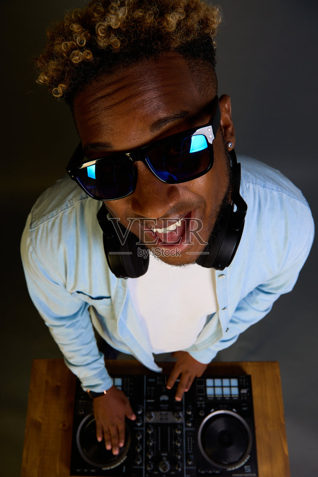 留着非洲式发型的非洲裔DJ戴着墨镜播放音乐。照片摄影图片