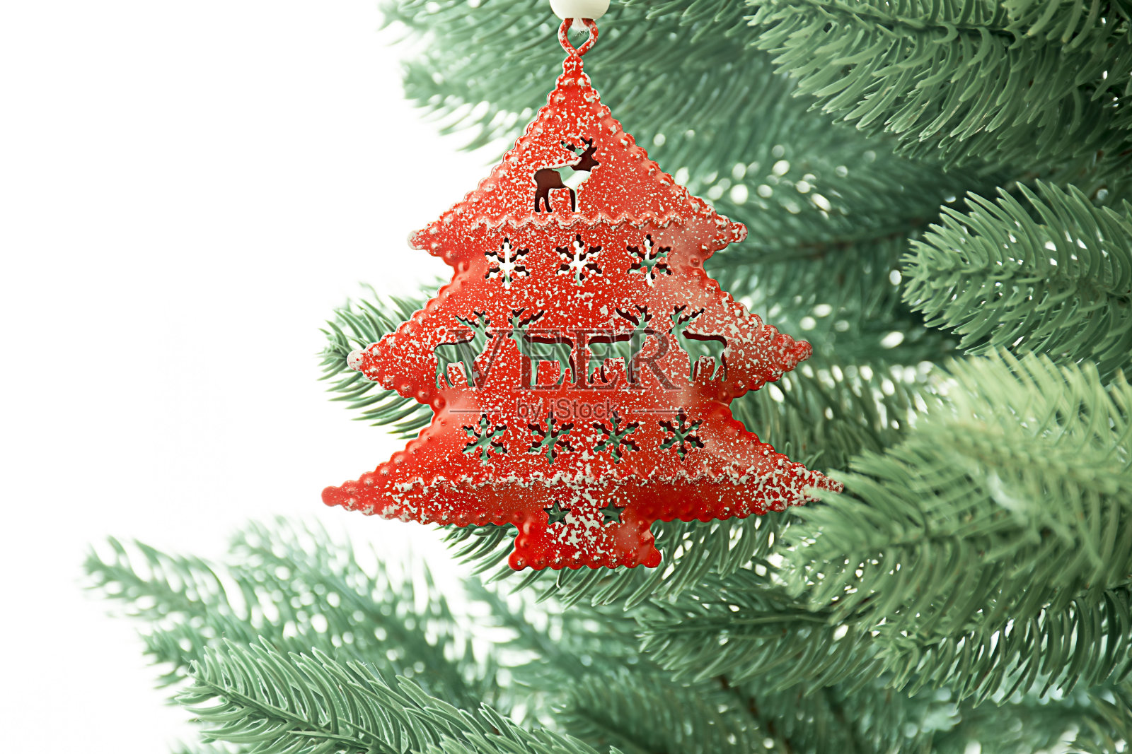 红色的圣诞树玩具压在白色背景的圣诞树上照片摄影图片