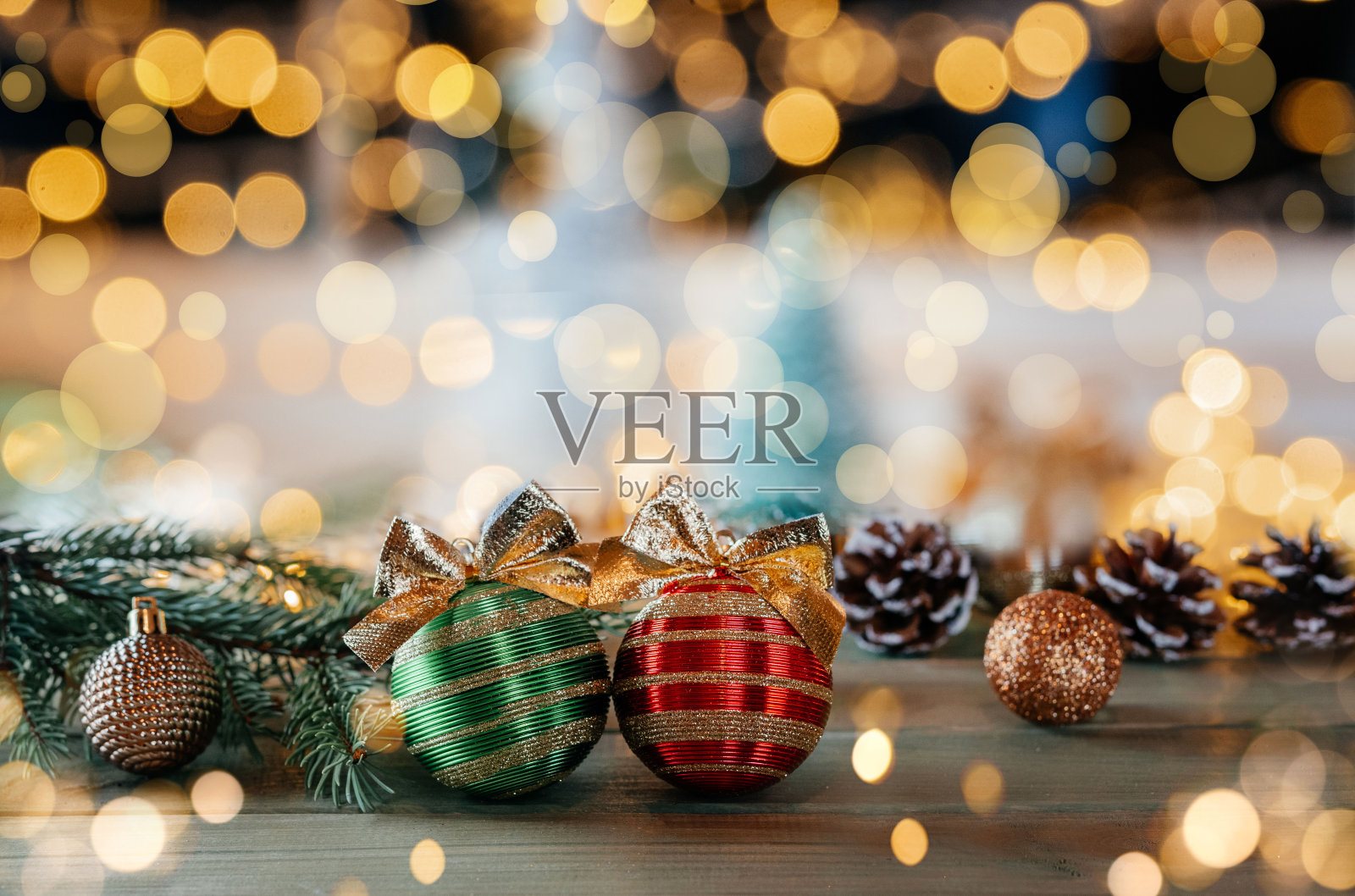 绿色和红色的圣诞灯泡与金色的蝴蝶结,冷杉树枝和装饰在木制背景与圣诞灯散景照片摄影图片