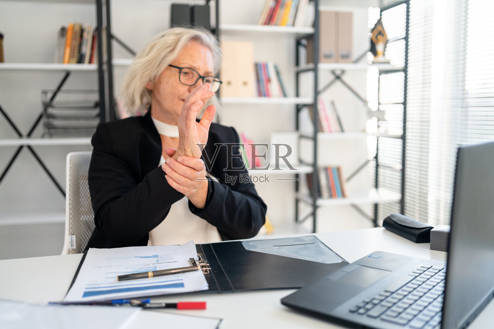 一位年长的女士痛苦地抓着他的手腕照片摄影图片