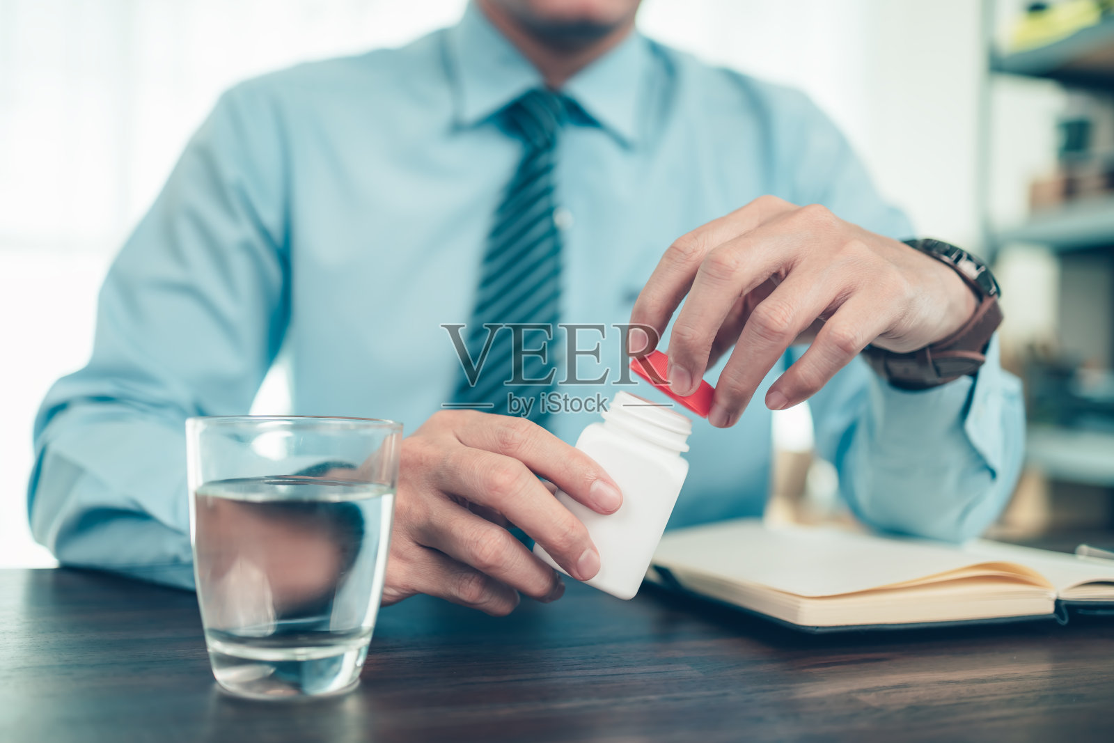 商人打开桌上的药瓶和水杯。照片摄影图片