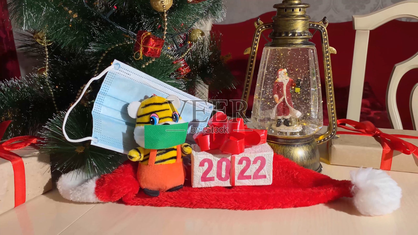 象征2022年新年的老虎带着防护面具,圣诞灯带着圣诞老人和新年树。冠状病毒大流行期间的安全假日庆祝概念。照片摄影图片
