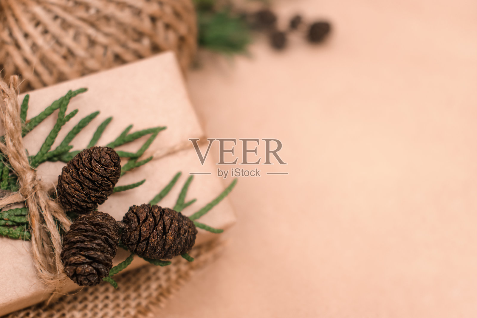 生态型节日礼品装饰。礼品盒用牛皮纸包裹,用棉线捆扎,用紫苏叶、球果和粗麻布装饰。圣诞节,新年和环保概念。照片摄影图片